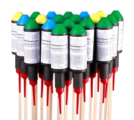 Mehrere bunte Farbenraketen mit grünen, blauen und gelben Köpfen, roten Zündschnüren und Holzstäben, freigestellt auf weißem Hintergrund